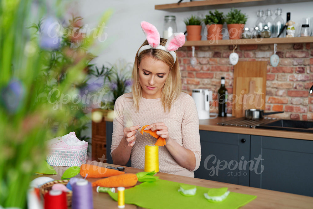 Beautiful woman in a rabbit's ears sews Easter decorations