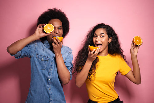 African couple have a fun with oranges in studio shot.