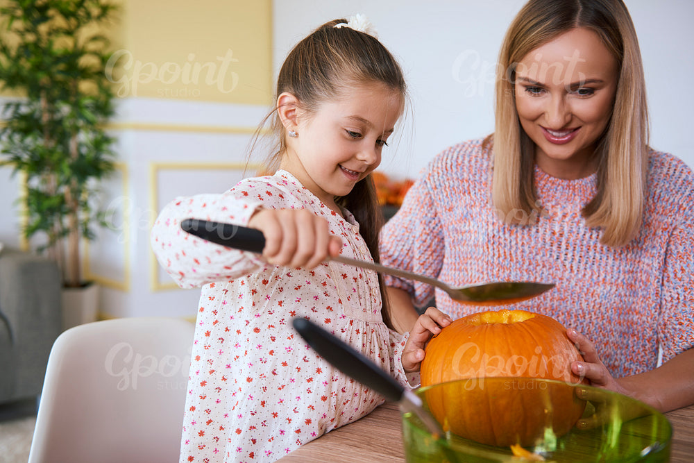 Mother helping daughter in carving pumpkins