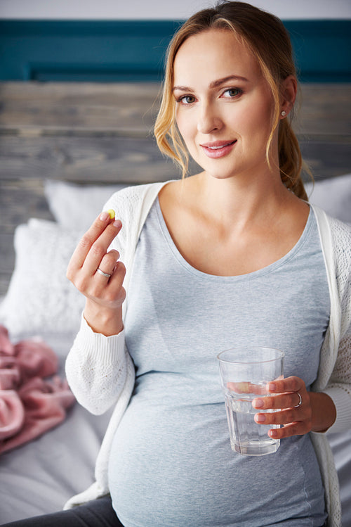 Portrait of young pregnant woman taking medicine