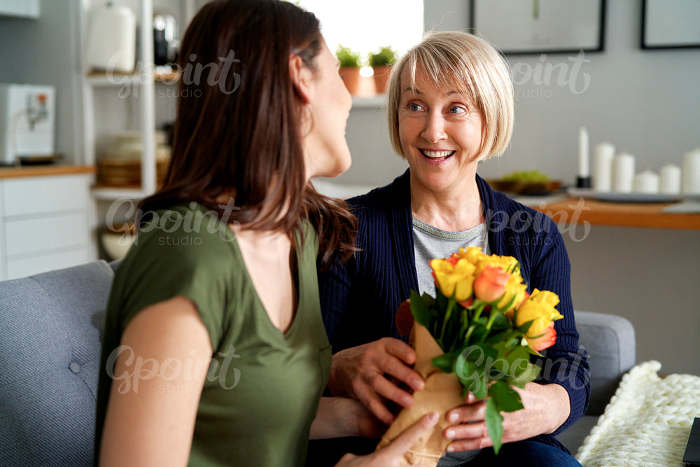 Surprised mother gets a bouquet of flowers from adult daughter
