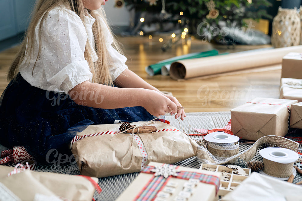 Caucasian little girl wrapping Christmas gifts on the floor 