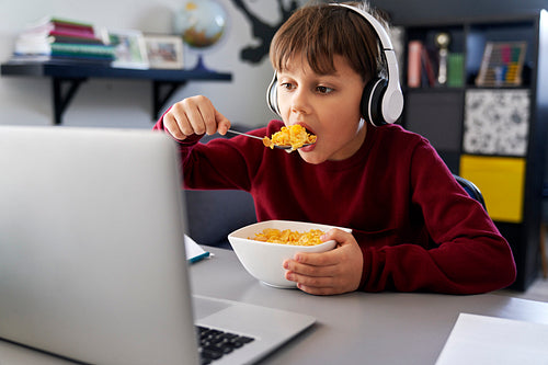 Boy eating breakfast during online classes