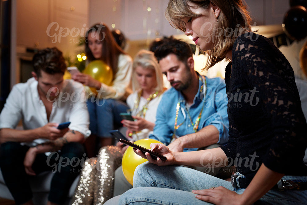 Friends focused on mobile phones on party