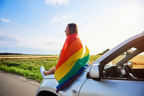 Young woman with rainbow flag enjoying the view
