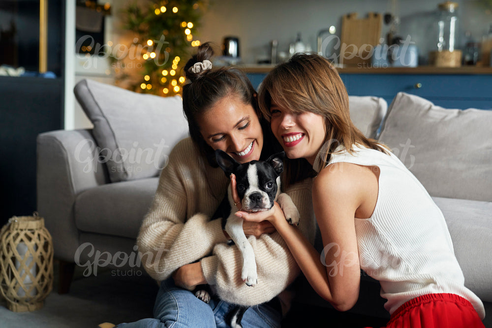 Two women hugging a puppy dog
