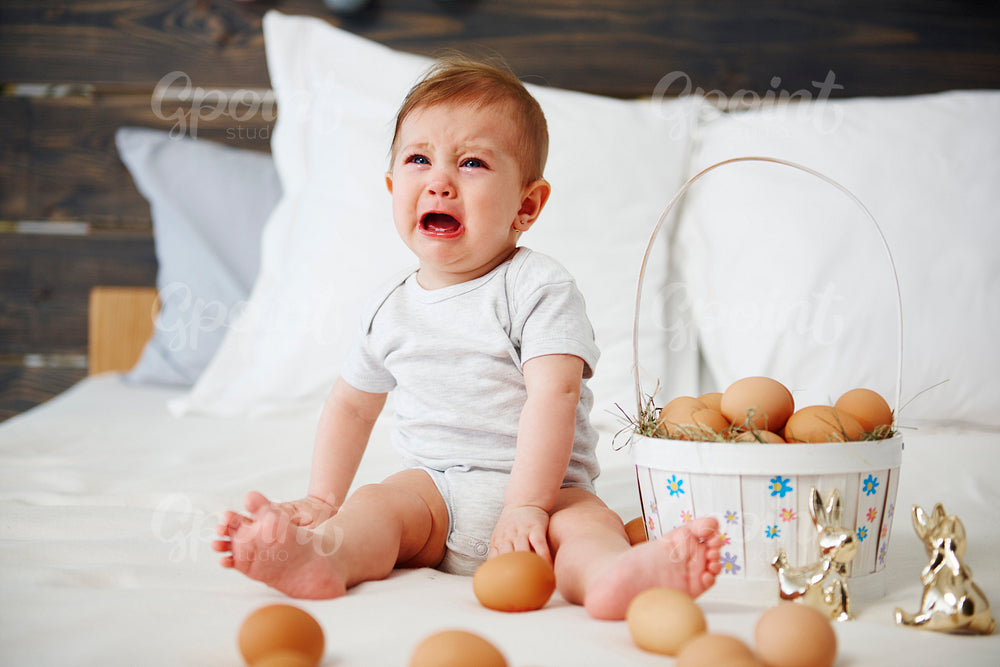 Crying baby celebrating Easter morning in bed