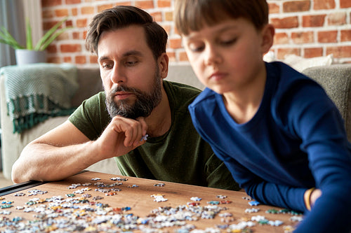 Close up of father and son solving jigsaw puzzle