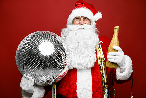 Caucasian Santa Claus celebrating with bottle of champagne and disco ball