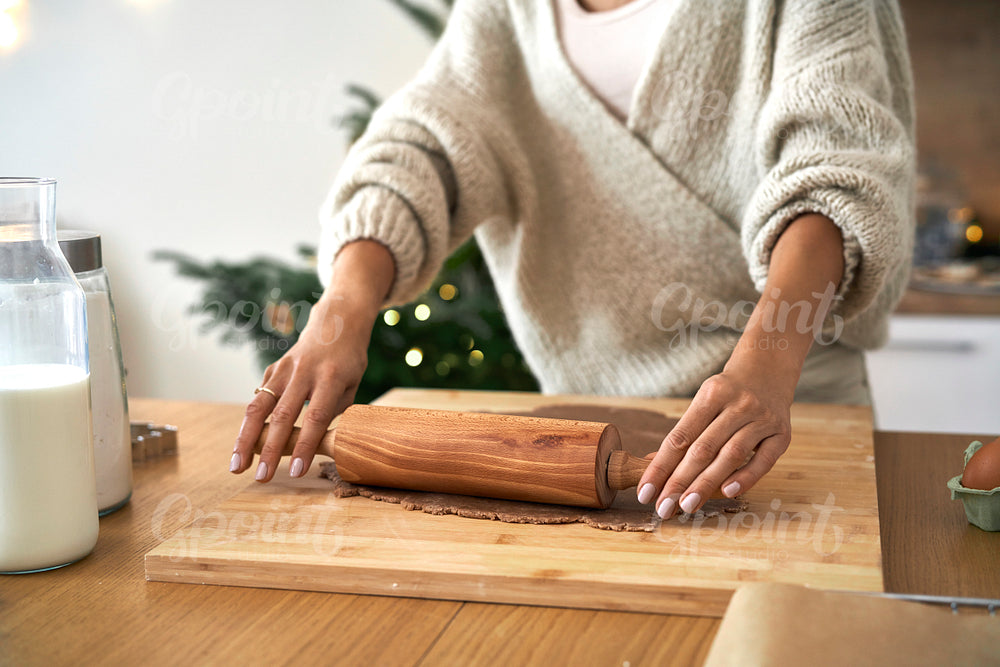 Close up of woman's hand rolling dough at the table in Christmas time