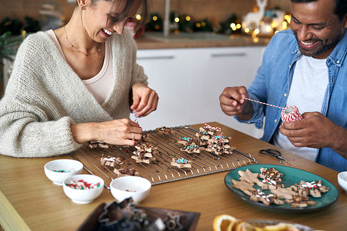 Couple decorating sweet cookies at home during the Christmas