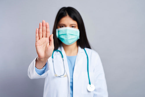 Doctor in face mask showing a hand stop symbol