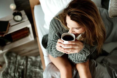 Attractive woman drinking coffee in bed
