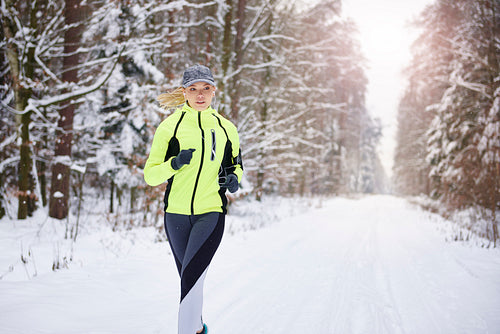 Front view of woman running in winter forest