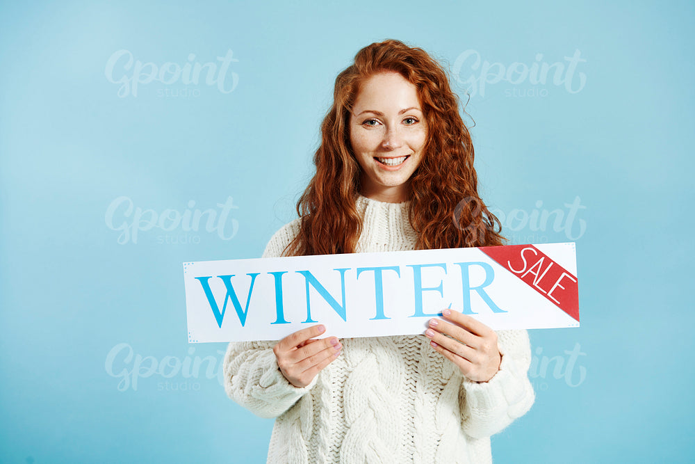 Portrait of smiling girl showing banner of winter sale