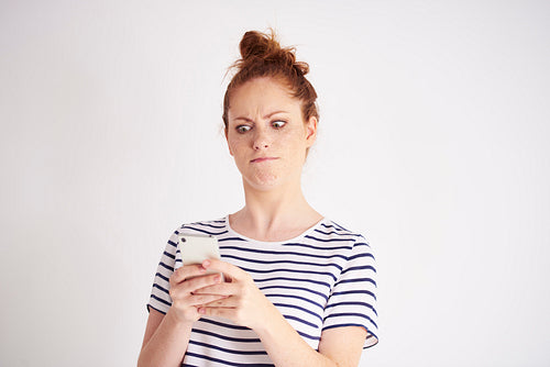 Furious woman using mobile phone at studio shot