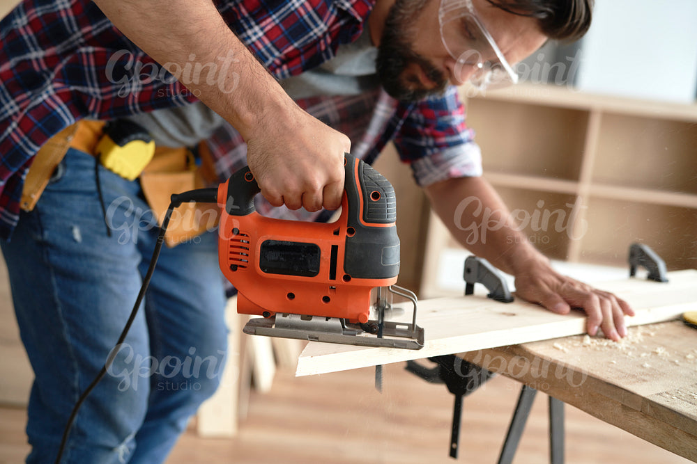 Carpenter using an electric jigsaw to cut wood