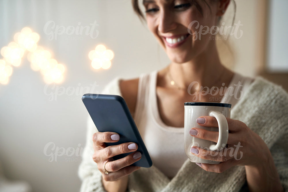 Close up of woman with cup and mobile phone in Christmas time