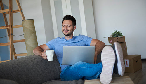 Man with laptop and coffee having break from moving house