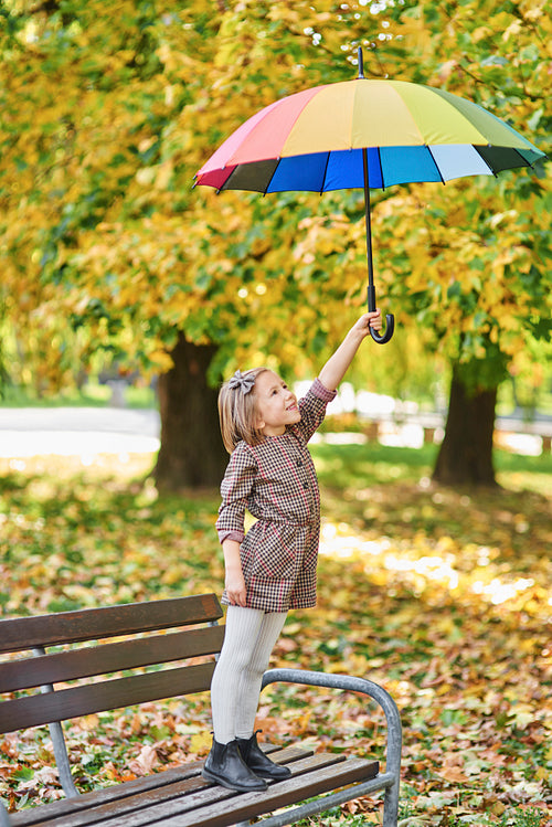 Charming girl with colorful umbrella in autumn park