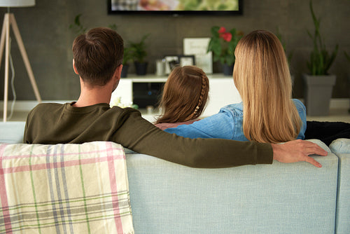 Rear view of family with one child watching tv