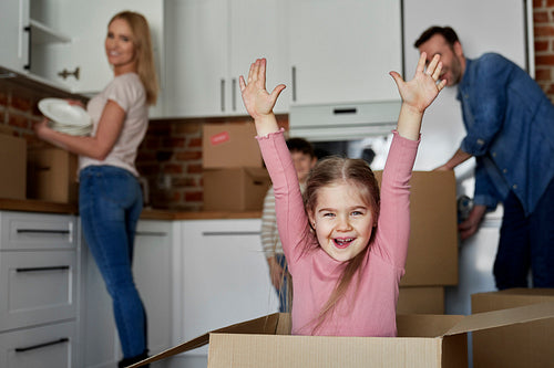 Portrait of a playful girl in a cardboard box while moving