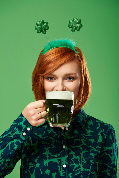 Portrait of young woman drinking beer in studio shot