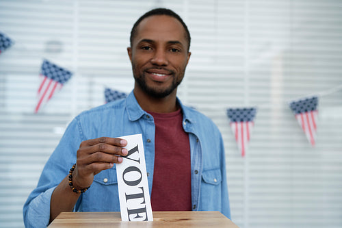 Portrait of black man giving his vote into ballot box