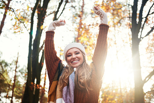 Portrait of beautiful woman with hands raised in autumn forest
