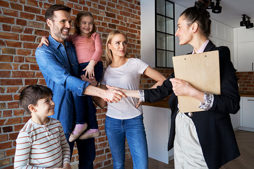 Family shaking hands with real estate agent in new apartments