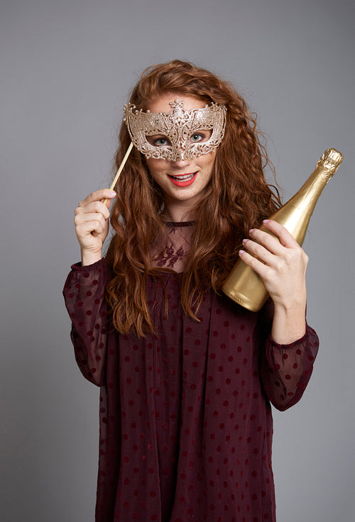 Portrait of girl with masquerade mask and champagne