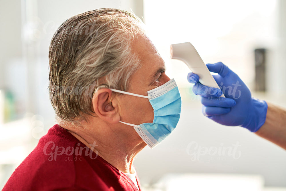 Side view of senior patient while taking the temperature
