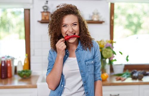 Young woman holding red pepper in her mouth