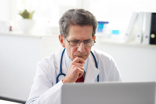 Senior doctor working with a laptop in doctor’s office