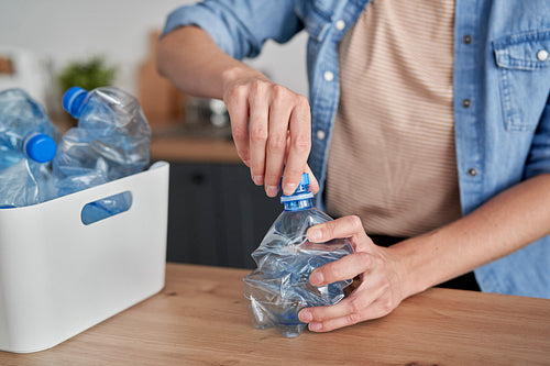 Woman crushing plastic bottles for recycling