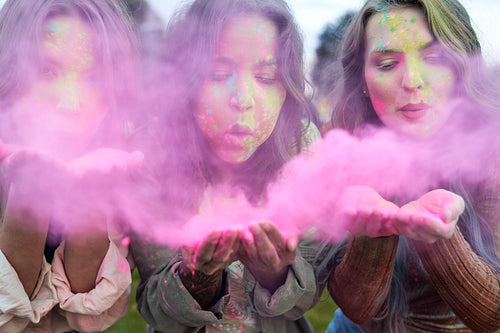 Group of women blowing coloured powder at music festival