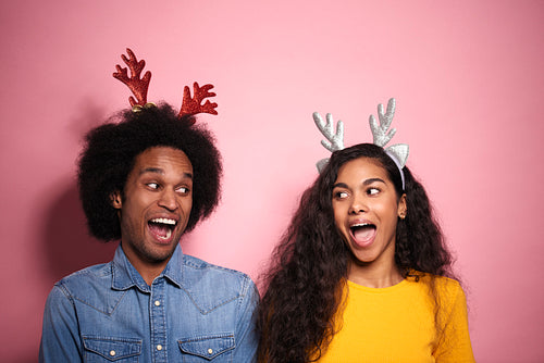 African couple screaming in reindeer headbands in studio shot.