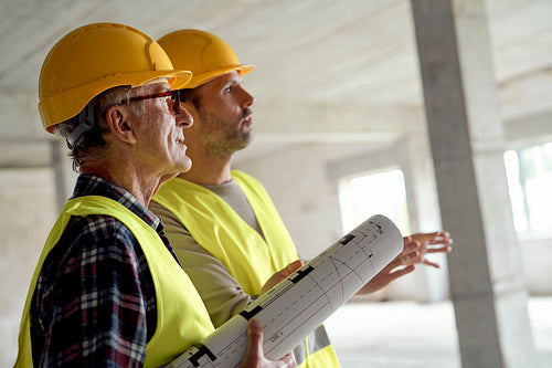 Close up side view of two caucasian engineers discussing on construction site