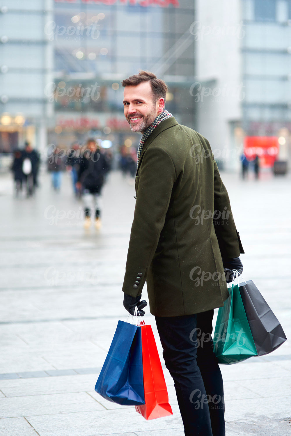 Turning man with shopping bags walking down the city street