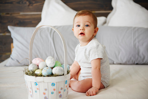 Adorable baby girl with basket of easter eggs