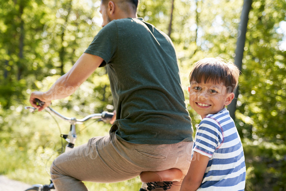 Portrait of boy riding a bicycle with his father in nature