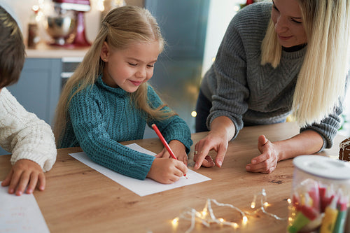 Girl writing a letter to Santa Claus with her mom