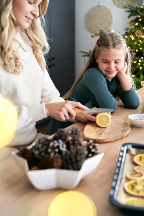 Caucasian mother and daughter preparing dried fruits for Christmas decorations