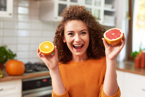 Beautiful woman having fun with fruit in kitchen