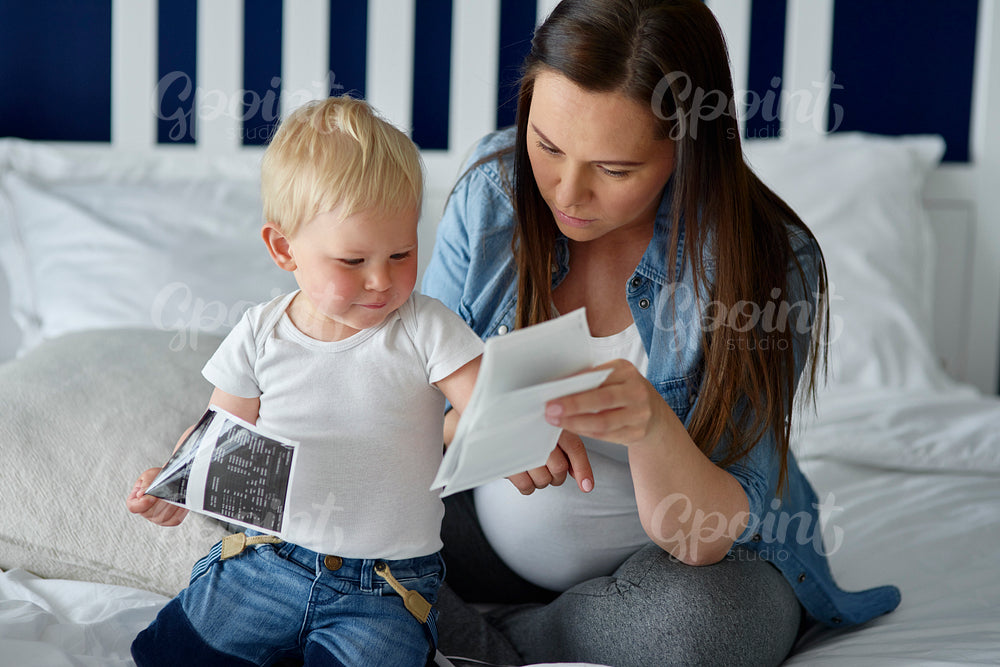 Pregnant woman browsing ultrasound images with her offspring