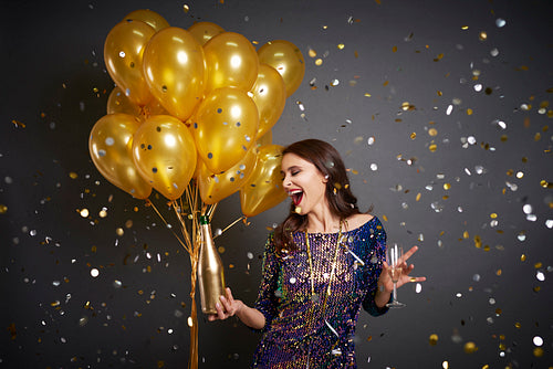 Woman with balloons and champagne among confetti