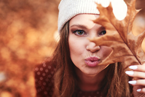 Woman in autumnal forest flowing a kiss