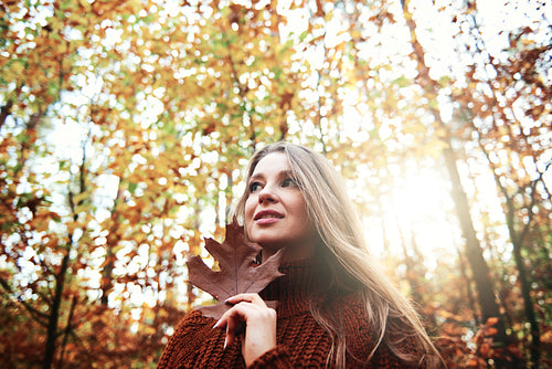 Beautiful  young woman holding autumnal leaf