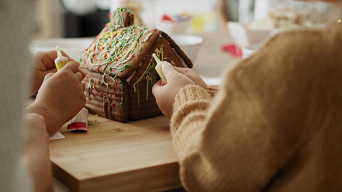 Detail video of children and mother decorating gingerbread house
