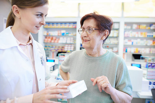 Female pharmacist assisting senior woman